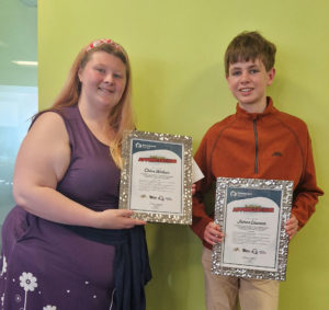 Chloe and James holding their certificates for their work sitting on interview panels