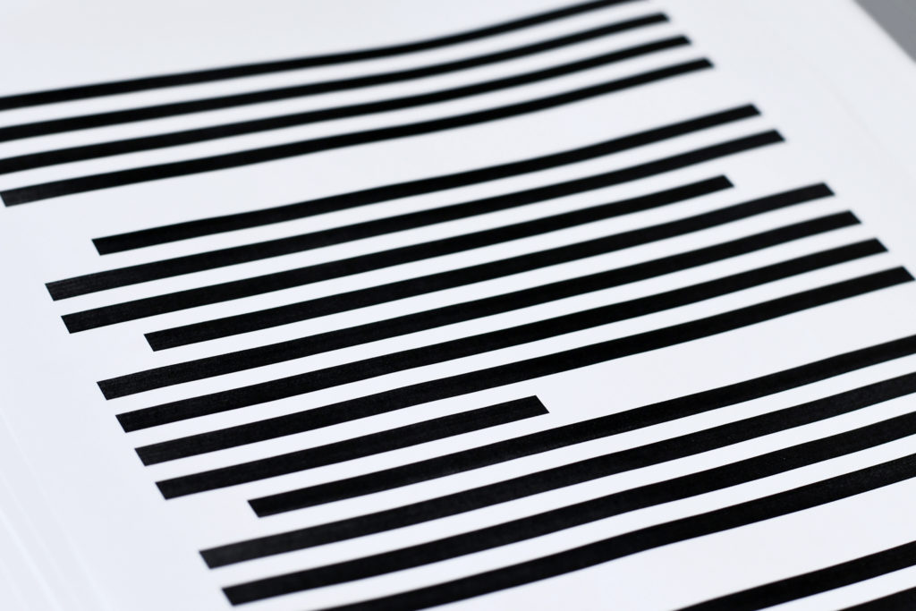 A redacted file, a white piece of paper with black lines covering text.
