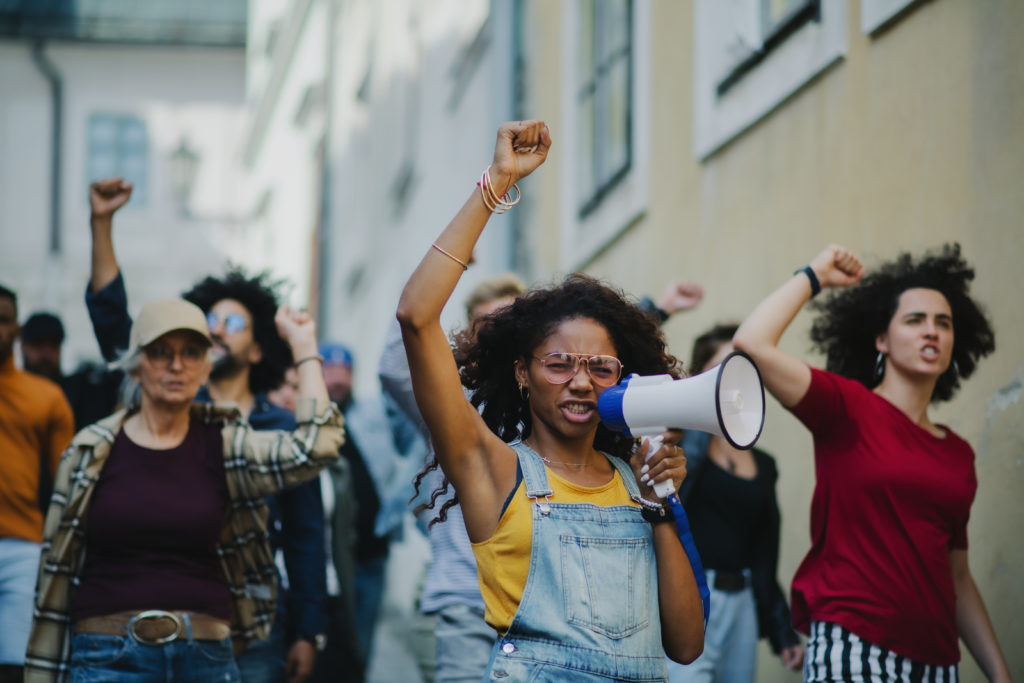People marching with a young woman in the front shouting into a megaphone