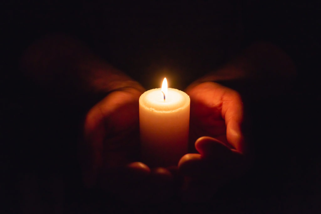 A single candle held in a pair of hands