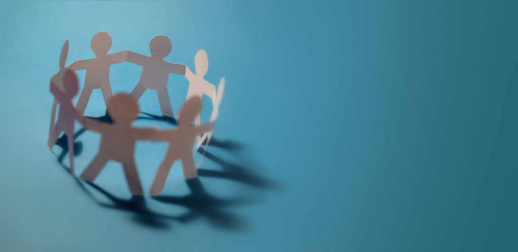 An image of different coloured paper dolls holding hands in a circle