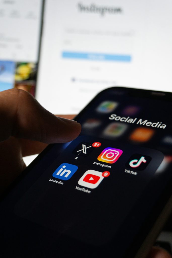 A photo of a close up of a mobile phone screen. On the screen are the words 'Social media' and app icons for multiple social media channels.