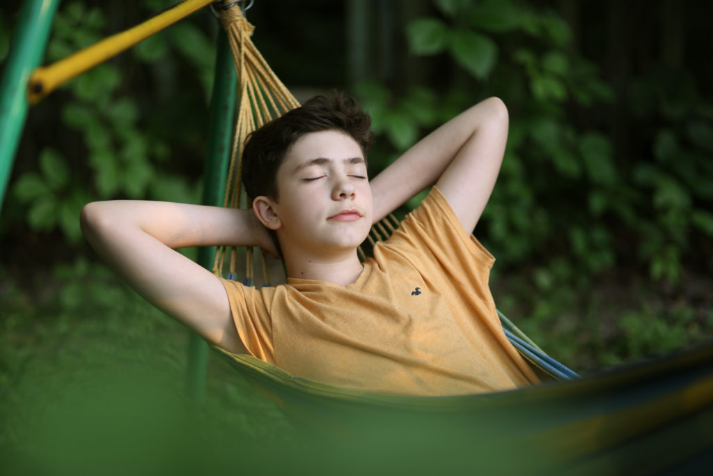 A photograph of a young person resting in a hammock.