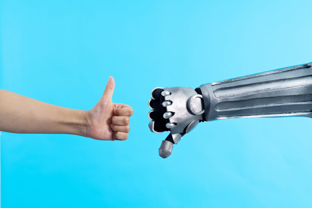 A human hand making a thumbs up gesture and a robot arm doing a thumbs down gesture.