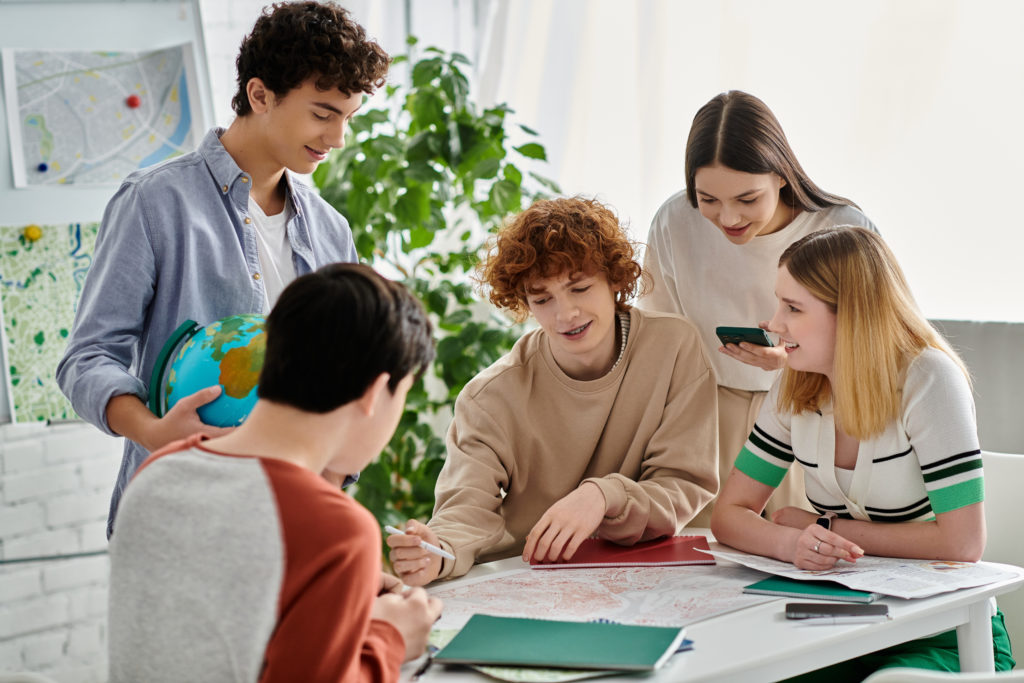 A group of young people discuss a topic while sat in a circle around a desk.