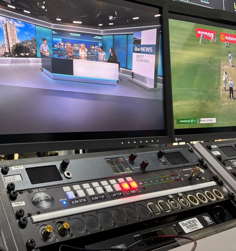 James, Archie and Grace sat at the counter at ITV News, as seen through a behind the scenes display.